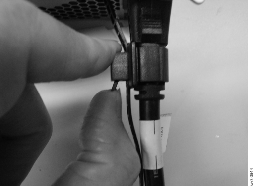 This photograph shows how you slide the cable retention bracket behind the power cord using the lever to release the cable tie.